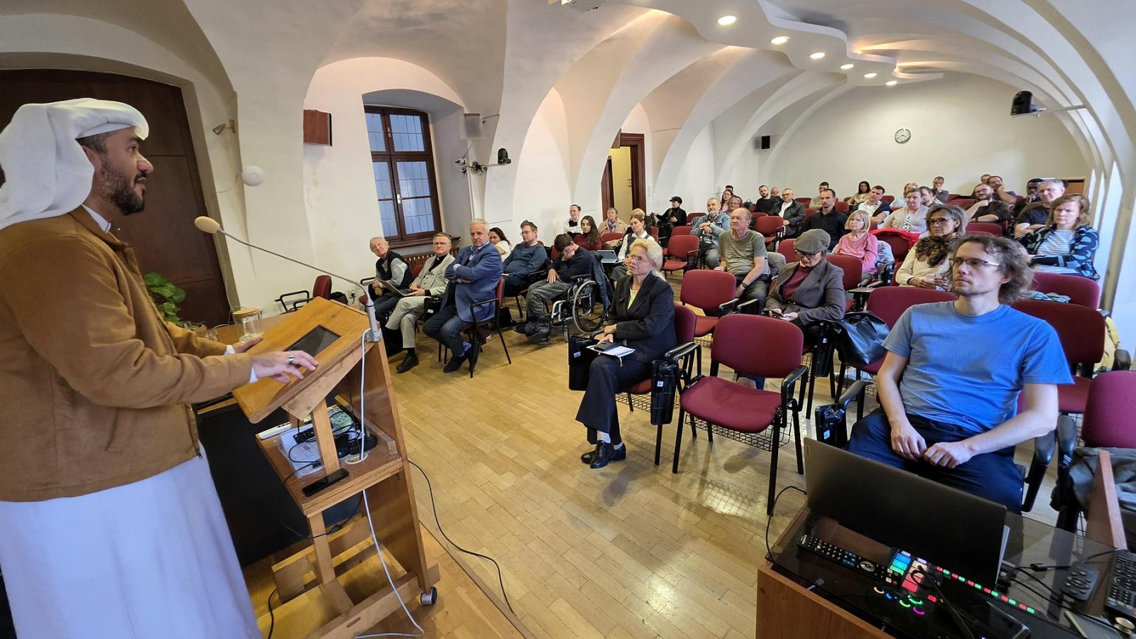 Loay Al Sharif hovorí pred účastníkmi v aule
